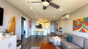 Un salon moderne doté d’un ventilateur de plafond, d’un canapé, d’une table basse et d’un coin repas avec des chaises.