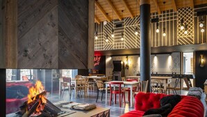 Een modern interieur met een open haard, rode zitplaatsen en een eetgedeelte met houten meubilair.