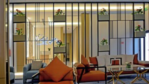 A modern hotel lobby with a seating area, a reception desk, and decorative plants. - AW Hotel Riyadh (Riyadh)