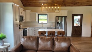 Een moderne keuken met witte kasten, een roestvrijstalen koelkast en een houten plafond.