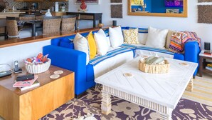 A modern living room with a blue sofa, white coffee table, and a chandelier.