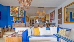 A modern living room with a blue sofa, a wooden coffee table, and a chandelier.