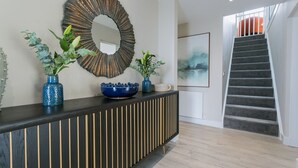 Una moderna recepción con una consola de madera, jarrones decorativos y un espejo grande.
