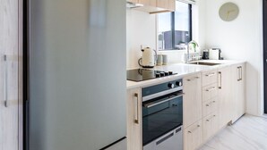 A modern kitchen with stainless steel appliances, light wood cabinetry, and a window providing natural light. - Upper Studio Perfection: 8 Wilmer St. Gem (Christchurch)