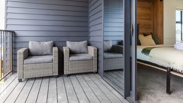 A room with two wicker chairs and a bed with a green blanket. - Upper Studio Perfection: 8 Wilmer St. Gem (Christchurch)