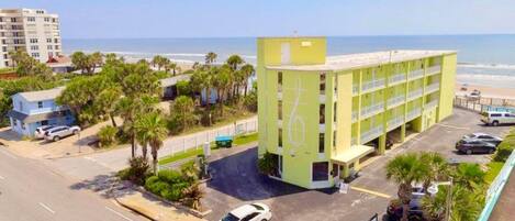 A multi-story hotel with a beach view, parking area, and a sign indicating '1 DBAAR'.