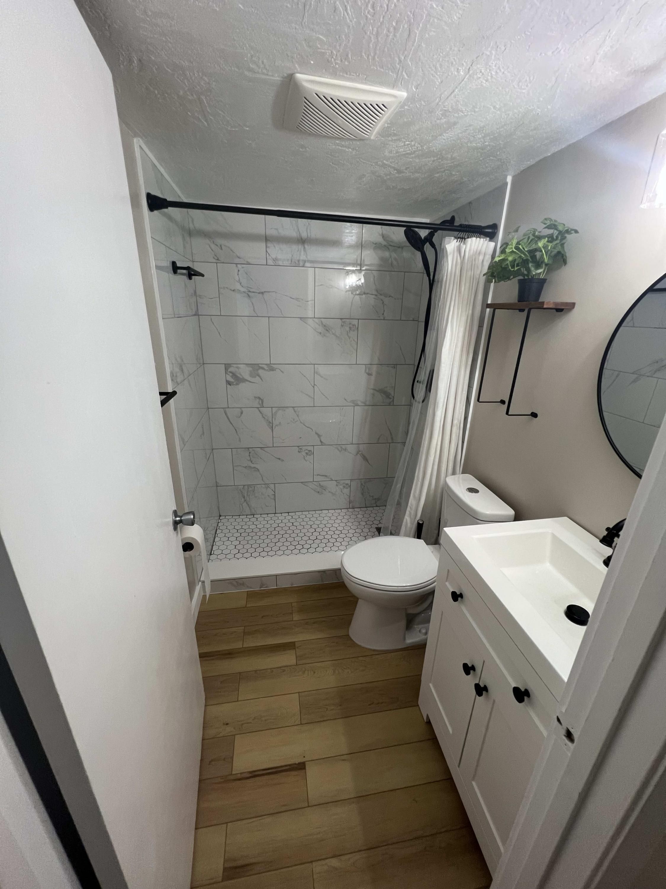 Un baño pequeño con ducha, inodoro y lavamanos.