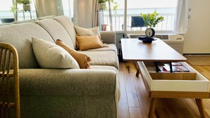 A living room with a sofa, a wooden coffee table, and a view of the sea through large windows. - The Lookout - Oceanfront at Symphony Beach Club (Ormond Beach)