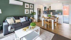 Un salon moderne comprenant un canapé, une table basse et un coin repas avec des chaises et une table.