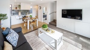 Un salon moderne avec un canapé, une table basse et un téléviseur fixé au mur.