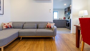 A modern living room with a grey sectional sofa, wooden flooring, and a red chair.