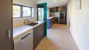 A modern kitchen with grey cabinets, a dishwasher, a sink, and a microwave.