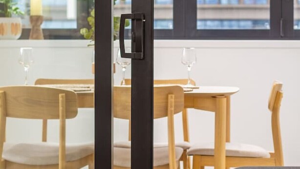 Zona pranzo moderna con arredi in legno e un divisorio in vetro.