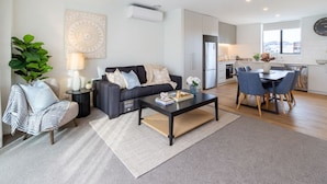 A modern living room with a sofa, coffee table, and a dining area with chairs and a table.