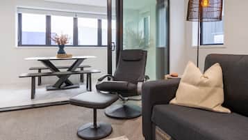 A modern living room with a sofa, a black chair, a dining table, and a floor lamp.