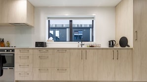Una cocina moderna con armarios de madera clara, horno empotrado y ventana con vistas a edificios.