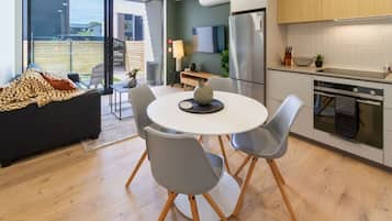 A modern kitchen with a dining area, a sofa, and a view of the outside.