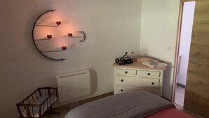 Un dormitori amb un llit, un prestatge, un radiador i una làmpada fixada a la paret.