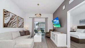 Ein modernes Hotelzimmer mit einer Couch, einem Couchtisch, einem Fernseher und einem Bett.