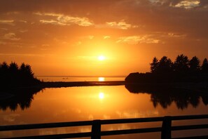 A sunset over a calm body of water with a wooden railing in the foreground. - Oceanview Cabin 28 w Jacuzzi Terrific Views (Smith River)