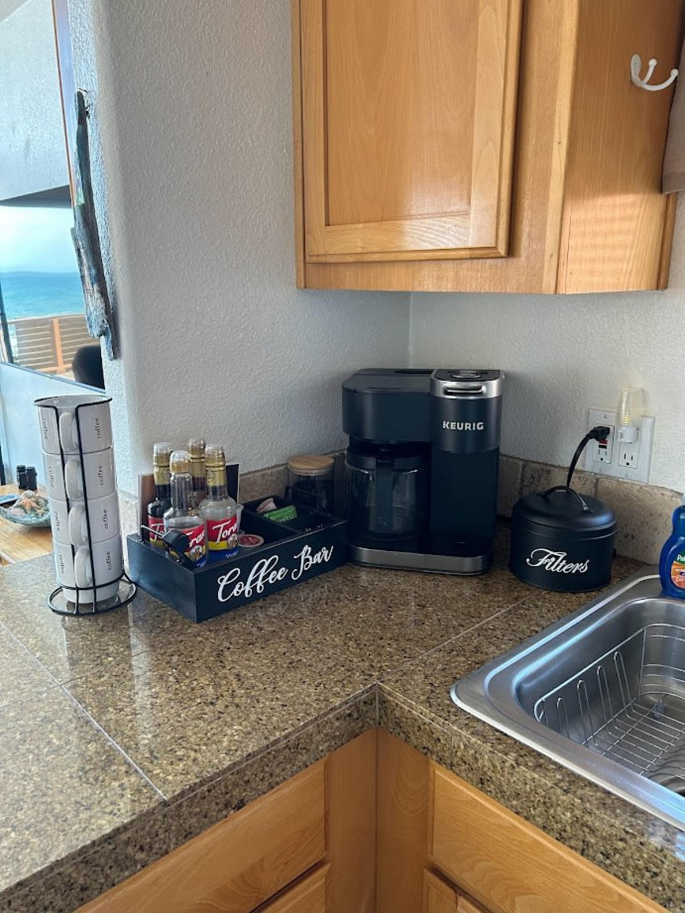 A kitchen with a coffee bar, a Keurig coffee maker, a water filter, and a coffee machine.