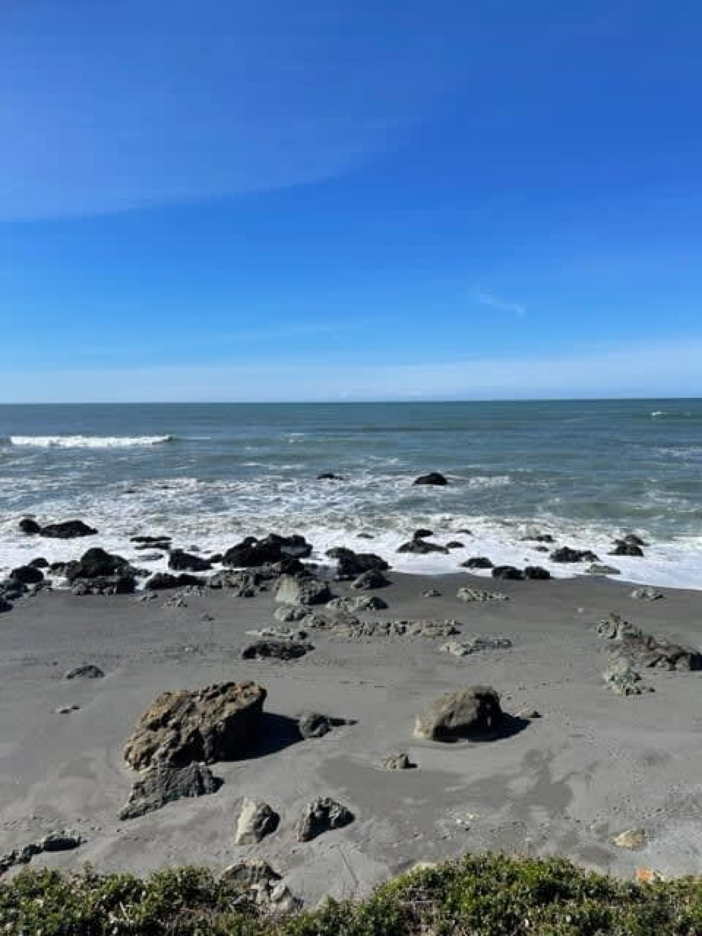 A beach with scattered rocks and waves.