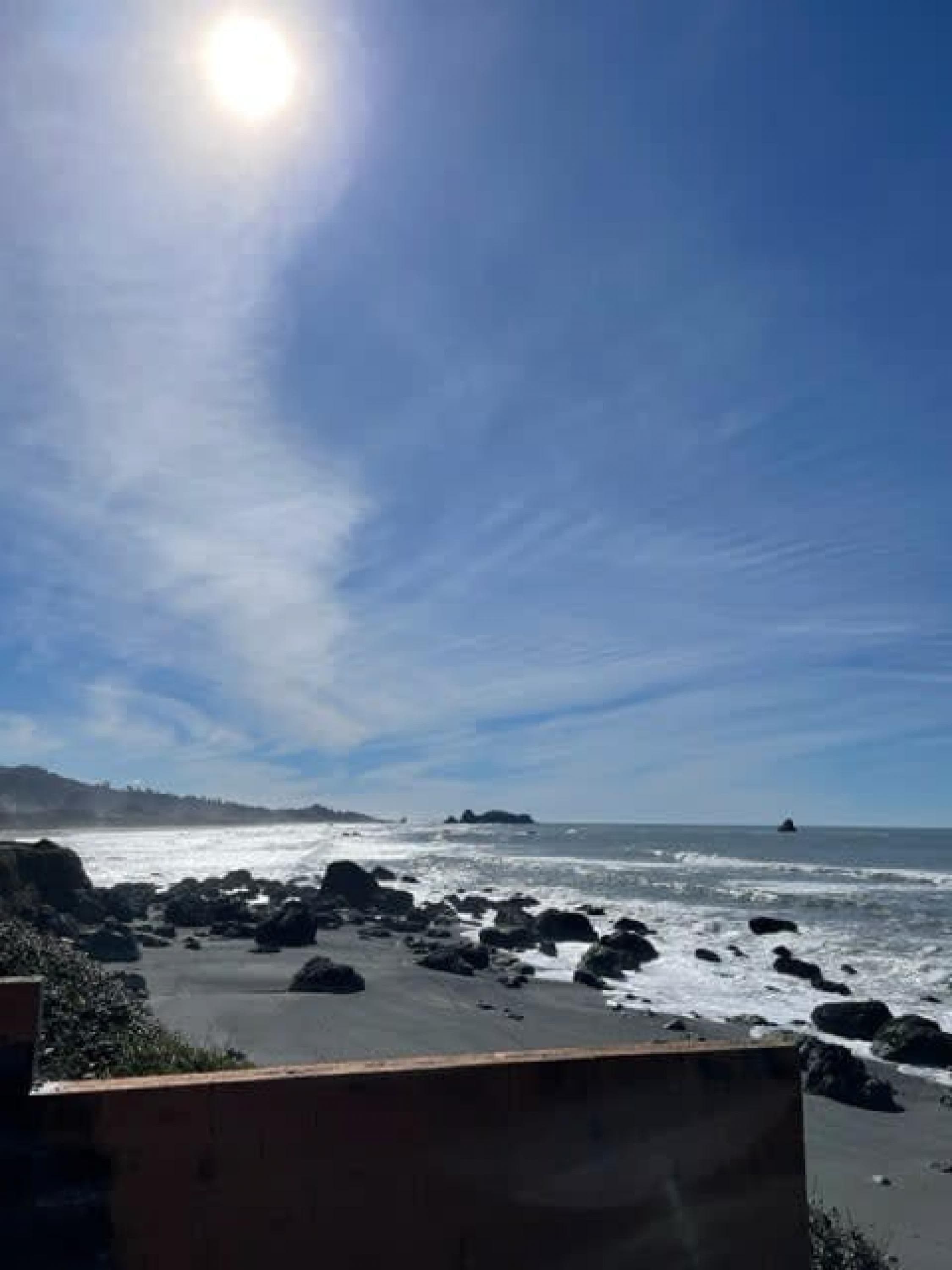 Una playa con terreno rocoso y cielo despejado.