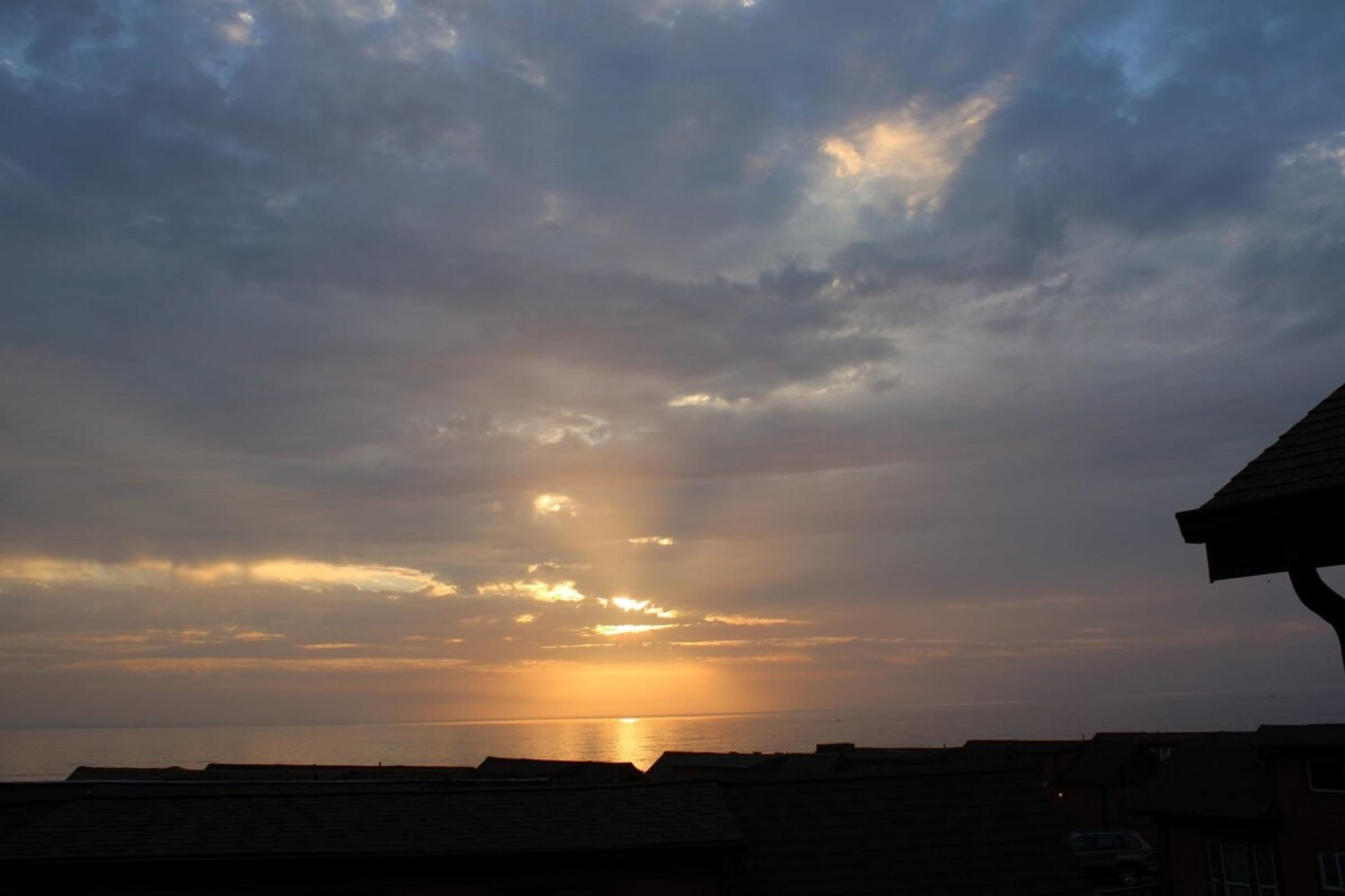 A sunset over a coastal area with buildings in the foreground.