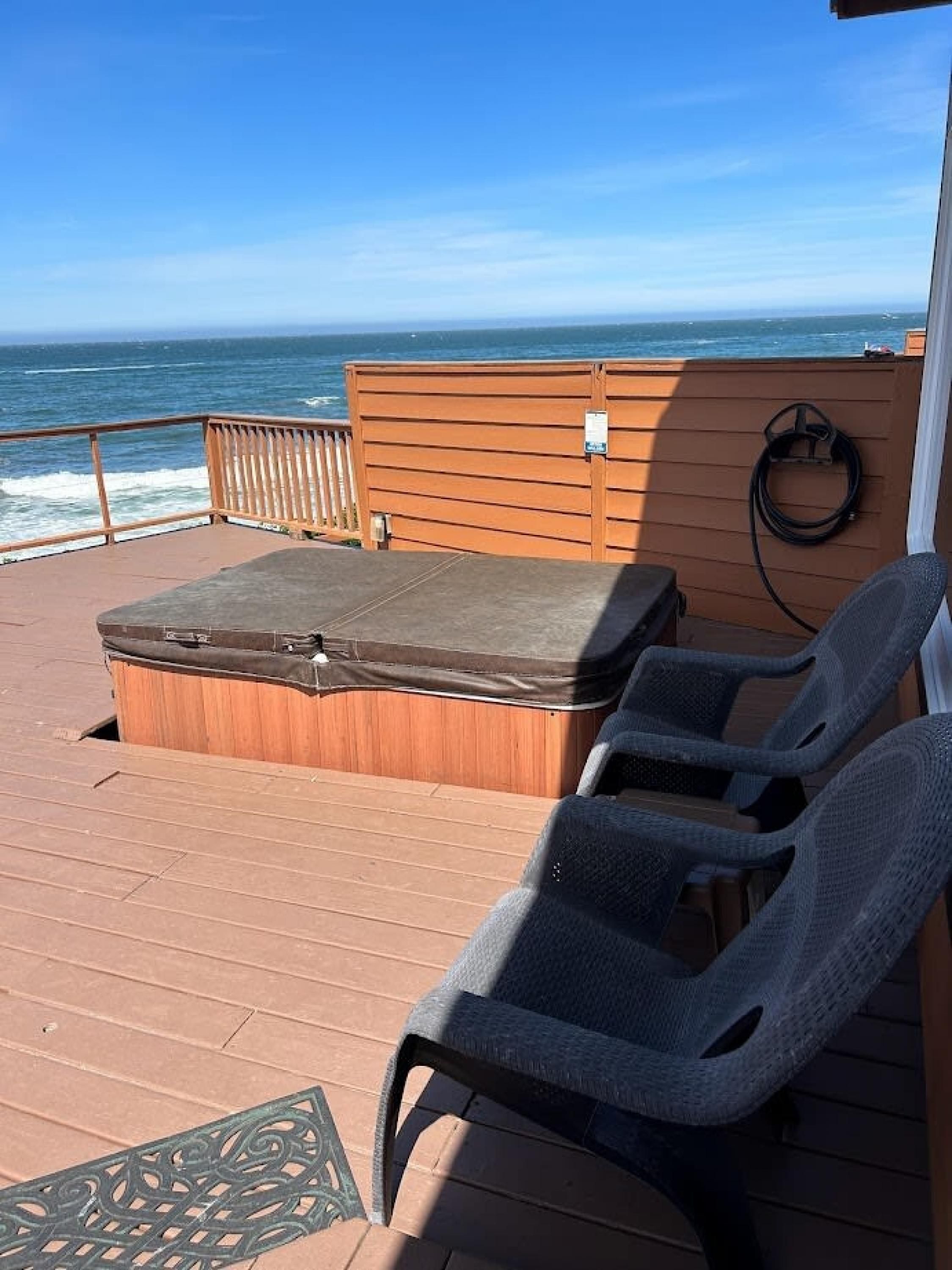 Une terrasse dotée d’un jacuzzi, de chaises longues et offrant une vue sur l’océan.