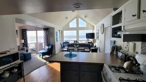Una cocina moderna con una isla central, un comedor con vistas y un espacio de sala con un amplio ventanal con vista al océano.