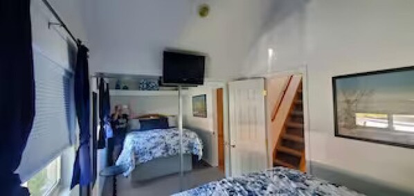 A bedroom with a bed, a TV, a window, and a door leading to another room. - Oceanfront Cabin 6 w Jacuzzi Awe-inspiring View (Smith River)