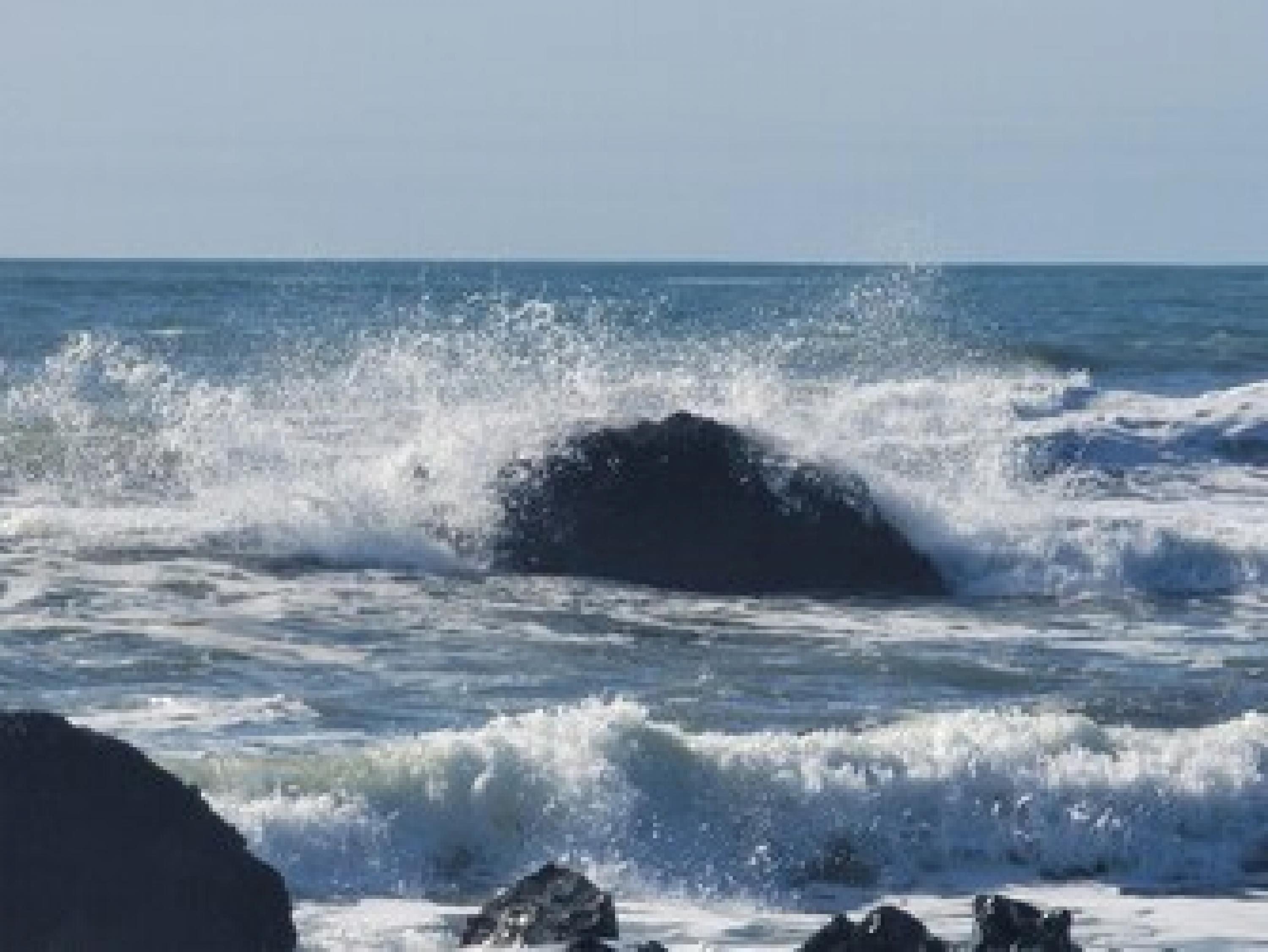 A coastal scene with waves crashing onto rocks.