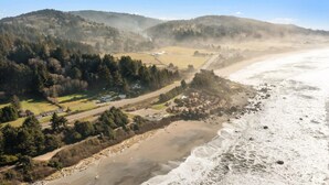 Un paysage côtier comprenant une plage, une route et une zone boisée.