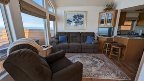 Un salon chaleureux avec un canapé, un fauteuil inclinable, un tapis et un tableau accroché au mur.