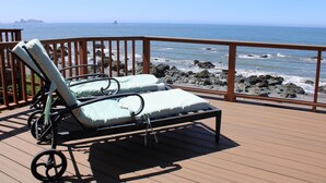 Une terrasse en bois avec deux chaises longues donnant sur l’océan.