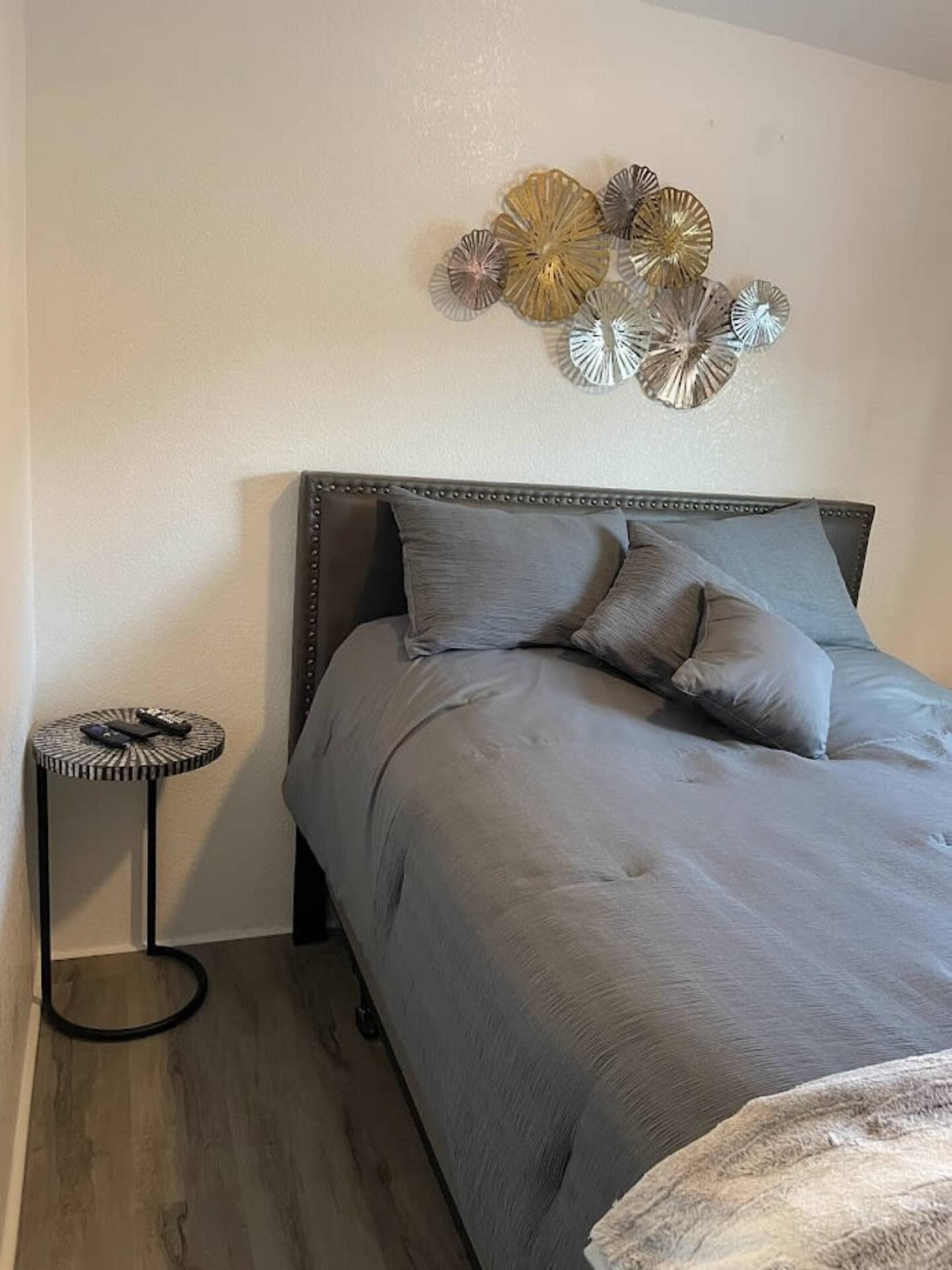 A bedroom with a bed, a round side table, and decorative wall art.