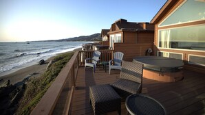 Una terraza de madera con mobiliario exterior, con vistas al océano.