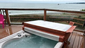 Ein Whirlpool auf einer Holzterrasse mit Blick auf den Ozean.