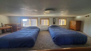 A room with two beds, a desk, a chair, and a dresser.