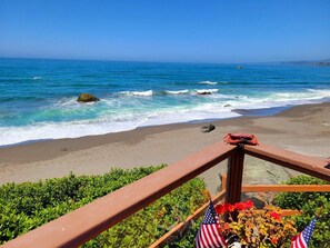 Une plage avec une rambarde en bois, des drapeaux américains et des fleurs.