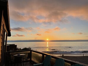 A terrace with a view of the sunset over the ocean, featuring a table and chairs. - Oceanfront Cabin 4 With Jacuzzi Stunning Views (Smith River)