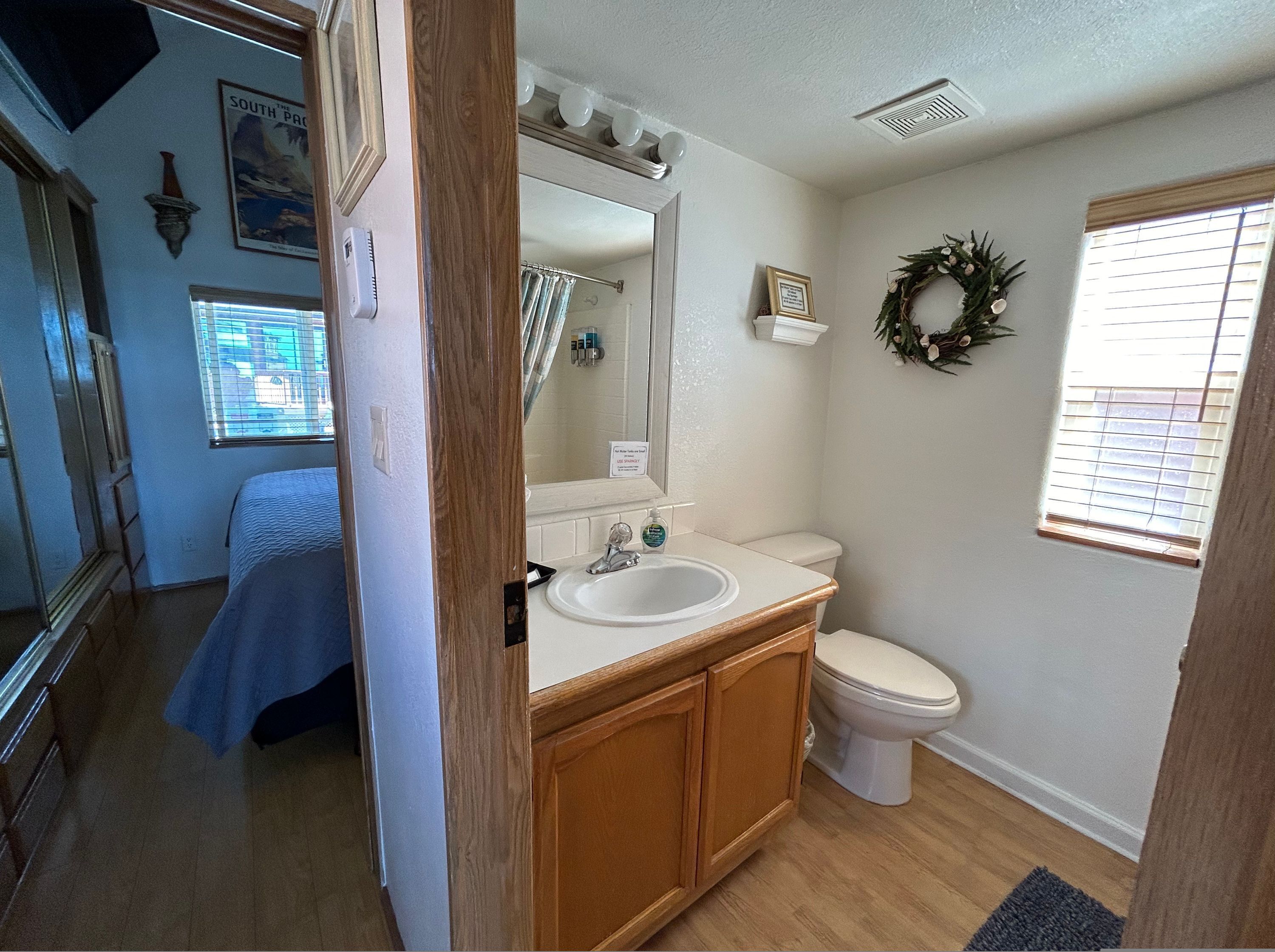 A bathroom with a wooden vanity, a white sink, a toilet, and a shower curtain.