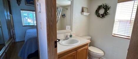 A bathroom with a wooden vanity, a white sink, a toilet, and a shower curtain.