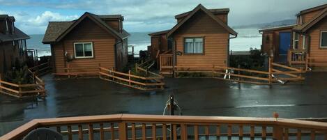 A wooden cabin with a deck, a view of the ocean, and a cloudy sky.