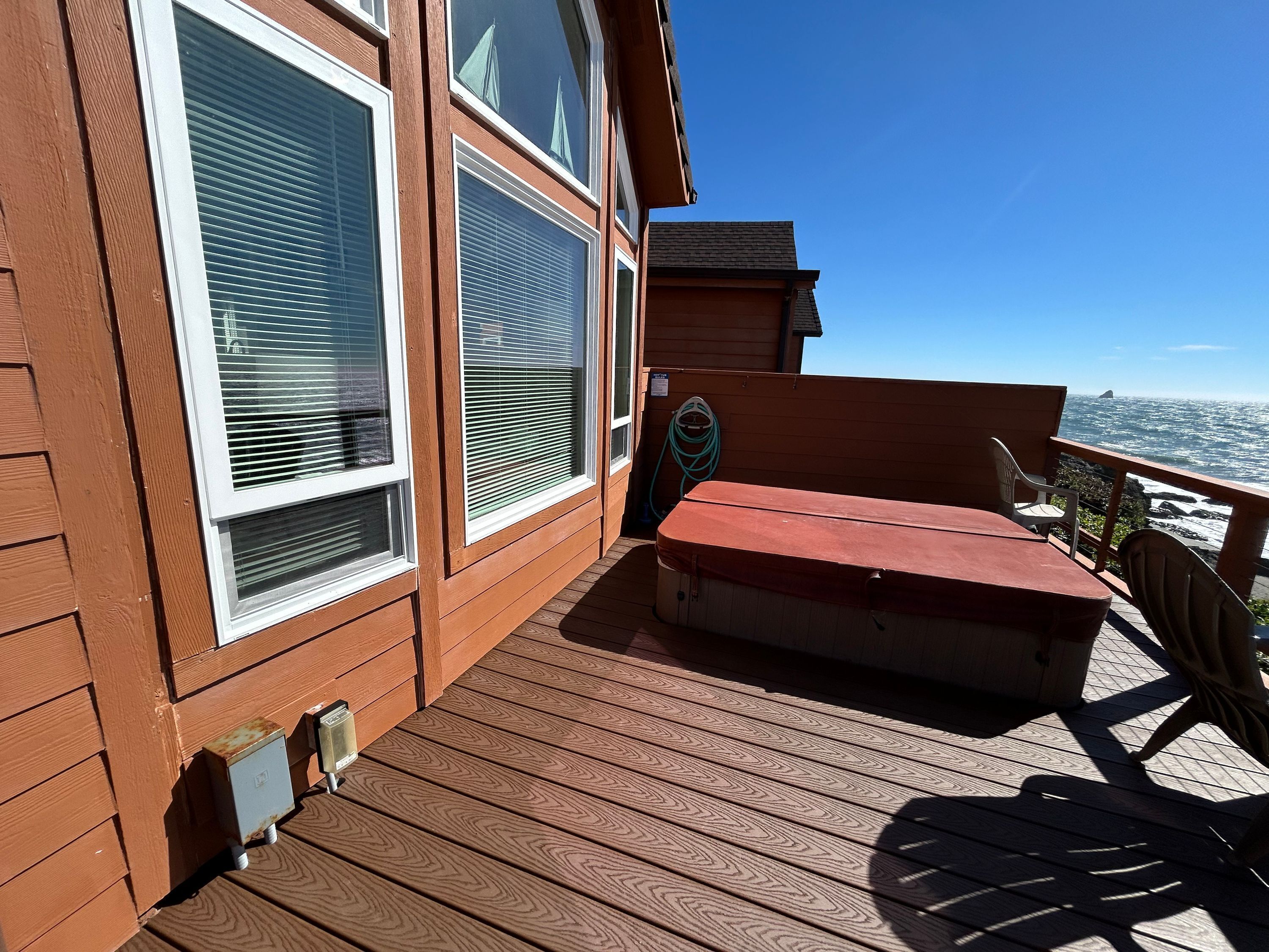 A wooden deck with a bench and a table, overlooking a rocky coastline.