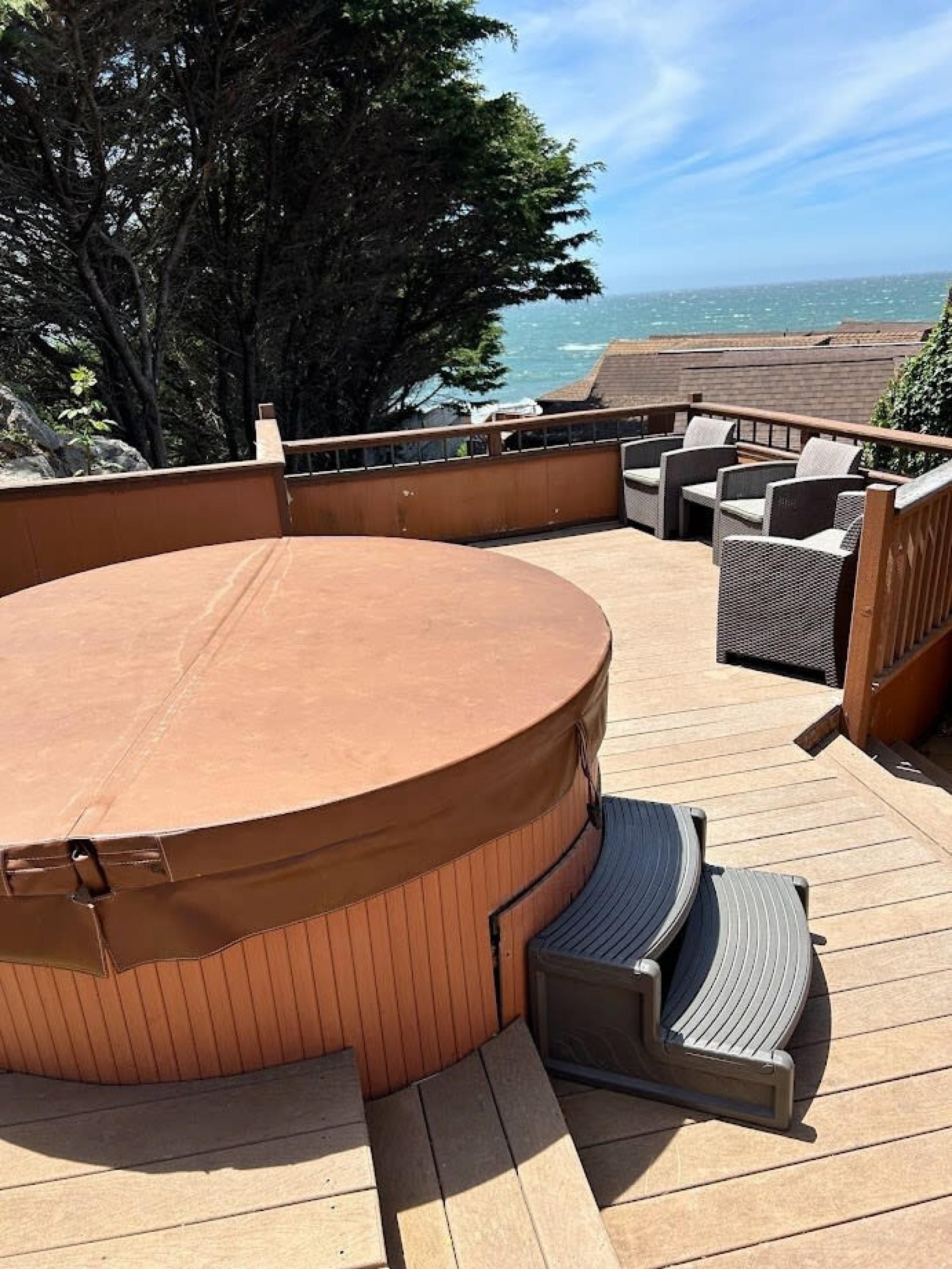 Eine Terrasse mit Whirlpool, Sitzgelegenheit und Meerblick.