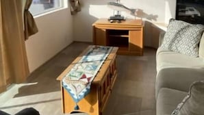Ein Wohnzimmer mit einer Couch, einem Couchtisch, einem Fernseher und einem Kamin.
