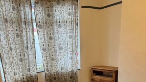 A room with a curved wooden floor, a wooden cabinet, and patterned curtains. - Stratford- (London)