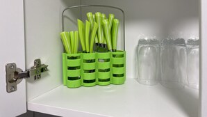 A kitchen cabinet with green utensil holders and clear glass cups. - Stratford- (London)