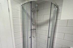 Huisje | Badkamer | Een douche, een haardroger, handdoeken